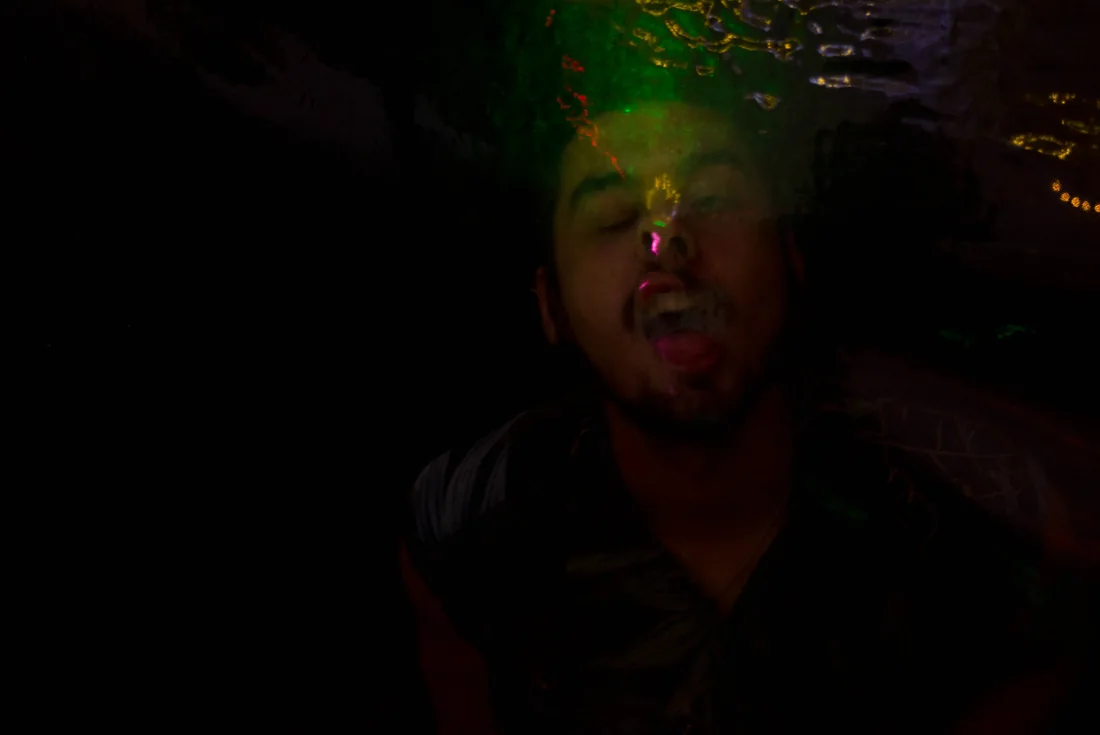 Man with his head tilted back, green laser light on his face