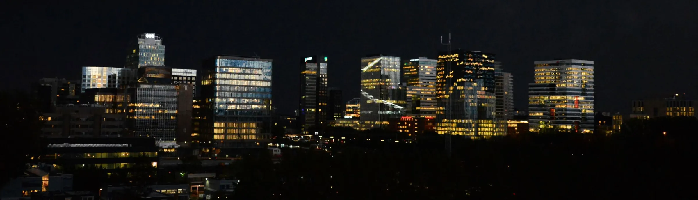 De kantoortorens van de Amsterdamse Zuidas bij nacht, met verlichte ramen