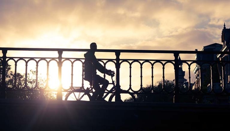 Foto van een fietser op een brug in Amsterdam